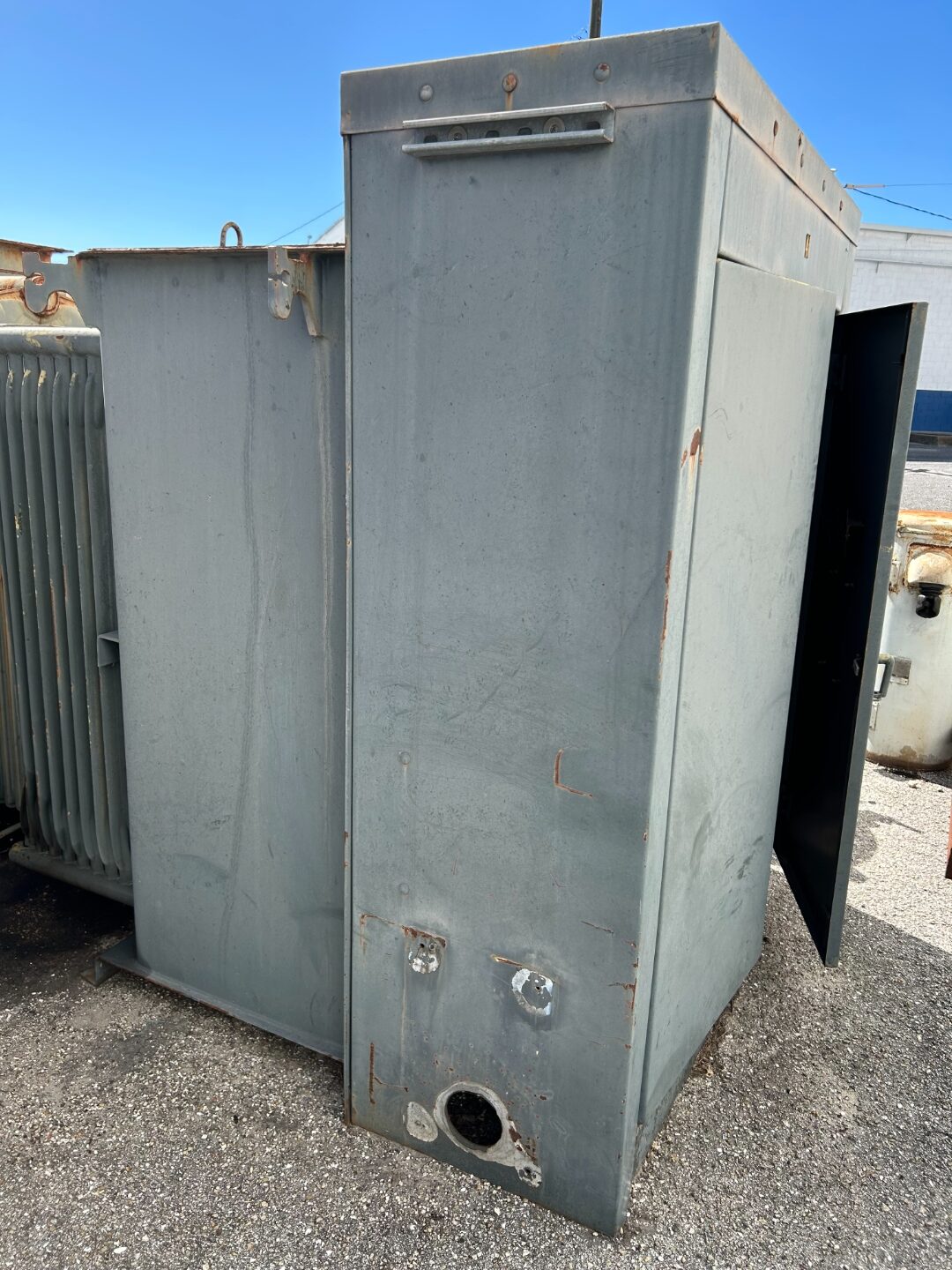 Large gray transformer tank with bushings and drain valve