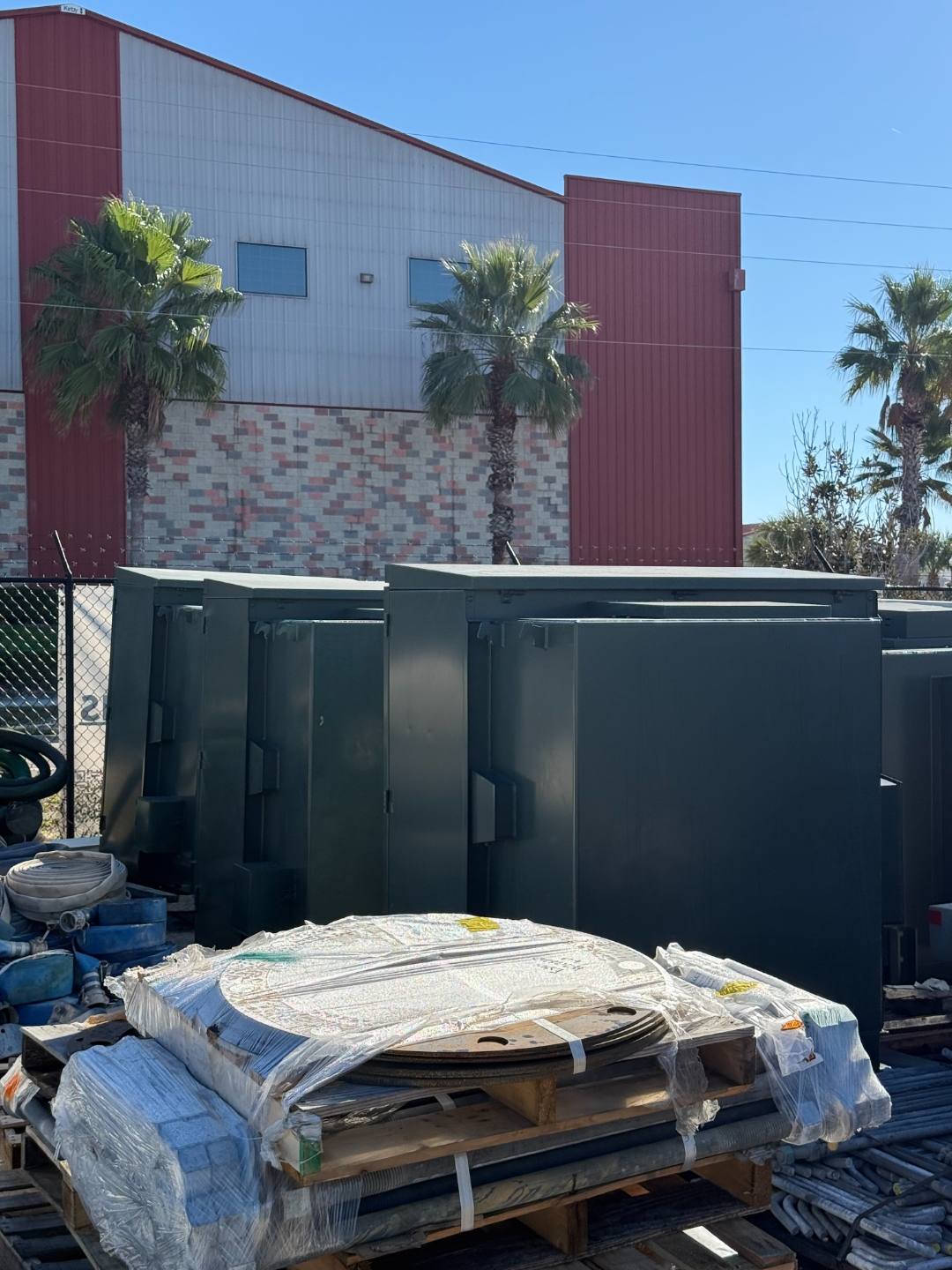 Pad-mount transformers staged on a pallet at an equipment yard