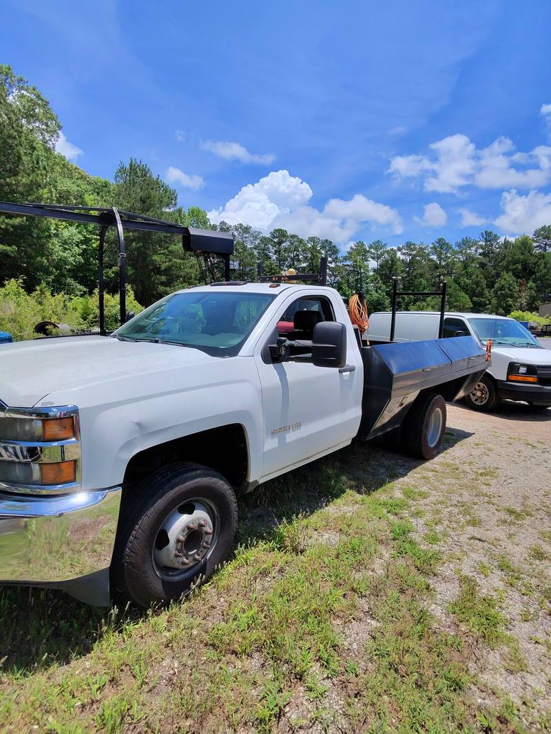 Contractor flatbed work truck with a cargo van behind it