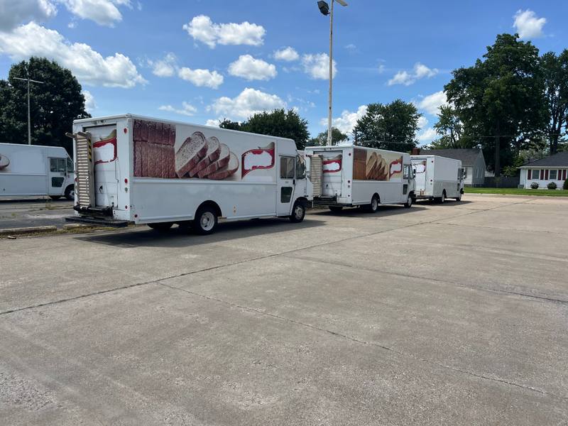 Row of white commercial step vans parked in a lot