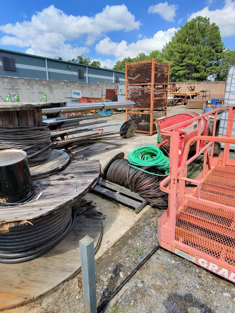 Industrial yard with cable reels, wire, metal stock, and lift equipment
