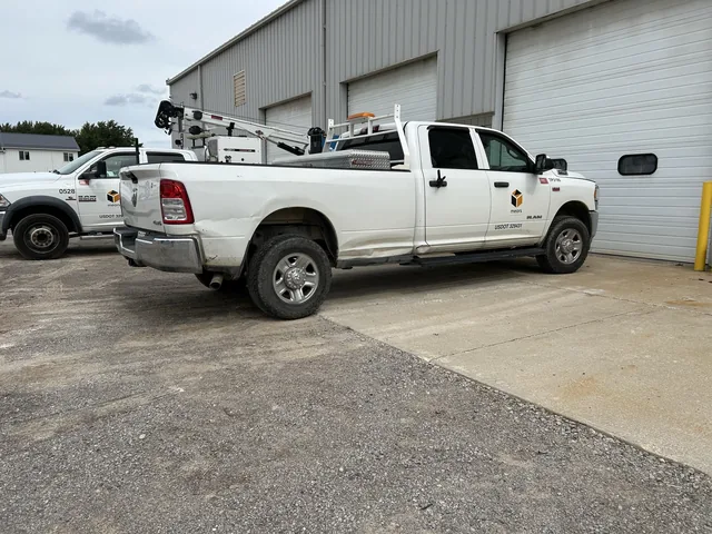 White crew-cab work pickup outside a shop